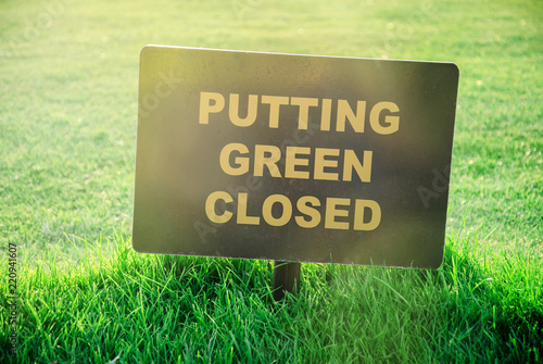 Putting Green Closed golf course sign in the gold course on a beautiful summer evening (focus on the grass)
