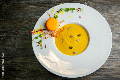 top view of fresh pumpkin cream soup with orange macaroon decoration