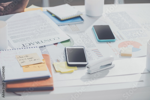 smartphones with contract and notebooks with stapler on table at modern office, business establishment