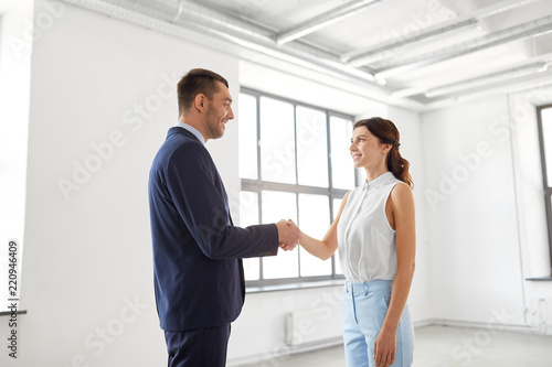 business people, partnership and cooperation concept - happy smiling businesswoman and businessman shaking hands at office