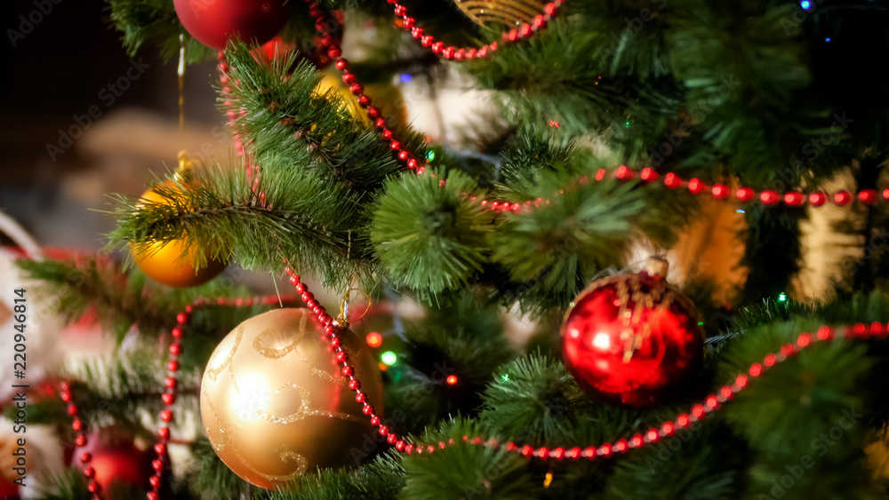 CLoseup photo of golden and red baubles hanging on beautiful Christmas tree