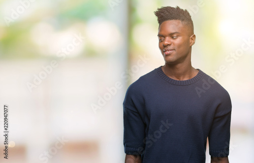 Young african american man over isolated background looking away to side with smile on face, natural expression. Laughing confident.