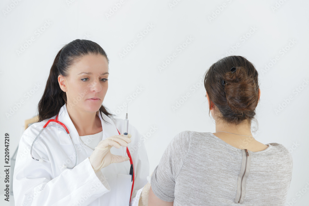 woman doctor with syringe in front of patient woman doctor with syringe in front of patient
