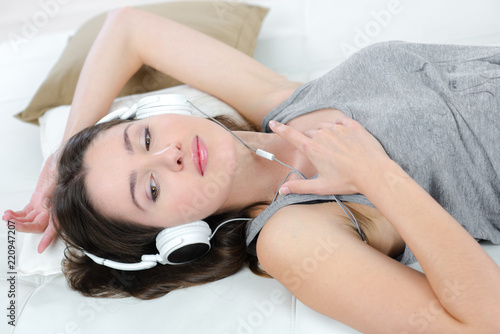 young female with headphones lying on bed