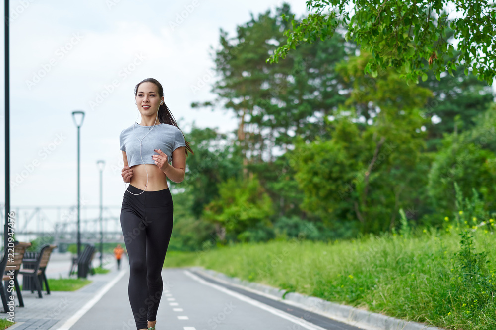 Running asian woman on the waterfront. Morning jogging. The athlete trains Running asian woman on the waterfront. Morning jogging. The athlete trains