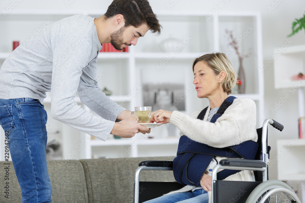 Fototapeta premium smiling woman on wheelchair with young male assistant