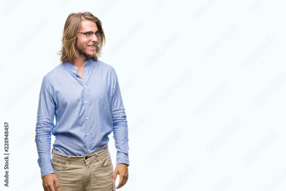 Fototapeta premium Young handsome man with long hair wearing glasses over isolated background looking away to side with smile on face, natural expression. Laughing confident.