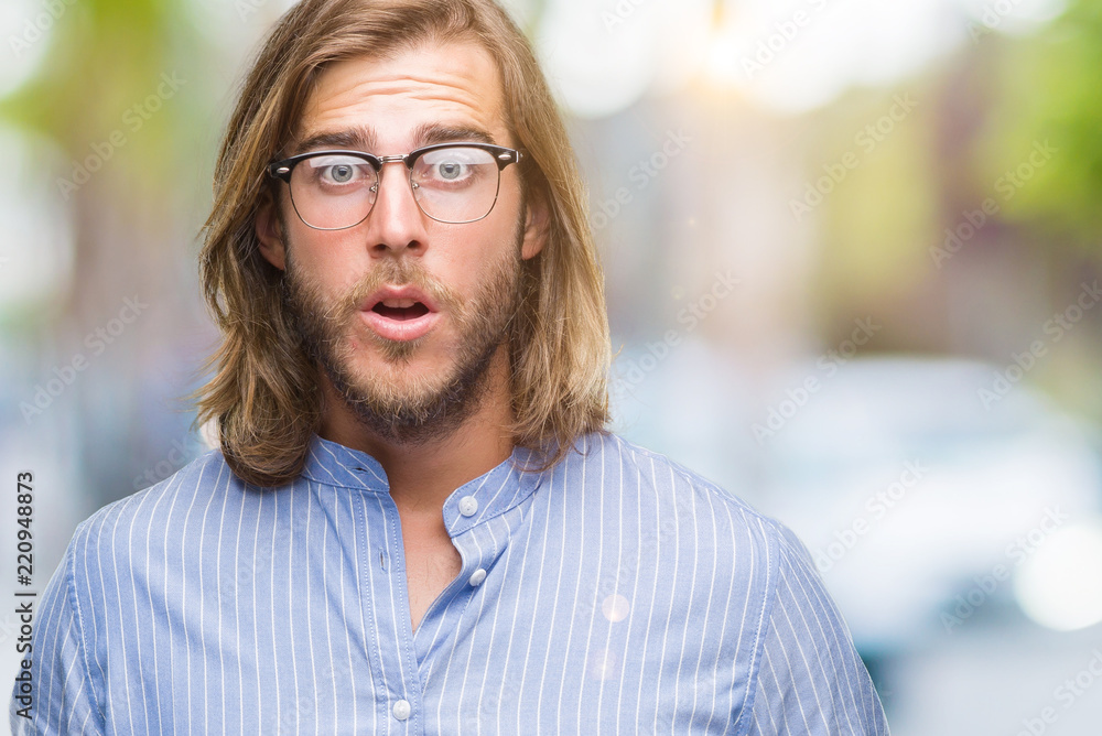Young handsome man with long hair wearing glasses over isolated background afraid and shocked with surprise expression, fear and excited face. Young handsome man with long hair wearing glasses over isolated background afraid and shocked with surprise expression, fear and excited face.