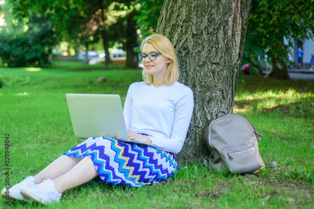 Lady freelancer working in park. Wi fi network connection free access. Woman with laptop works outdoor, park background. Taking advantages of free wi fi. Girl sit grass lean tree trunk with notebook Lady freelancer working in park. Wi fi network connection free access. Woman with laptop works outdoor, park background. Taking advantages of free wi fi. Girl sit grass lean tree trunk with notebook