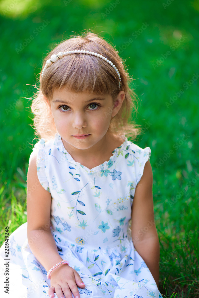 Portrait of a smiling little girl sitting on green grass. Portrait of a smiling little girl sitting on green grass.