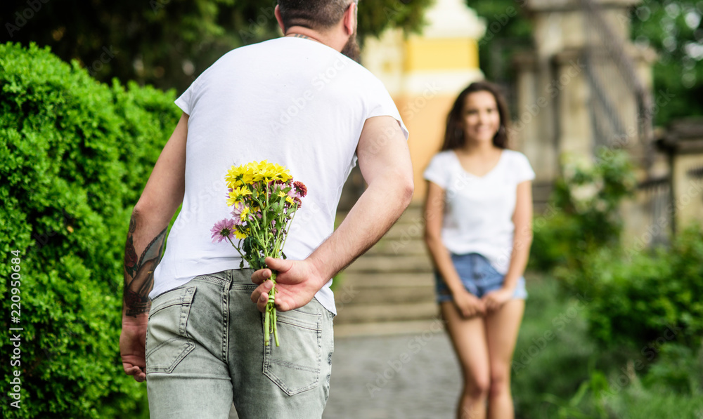 Man hides flower bouquet behind back while waits girl romantic