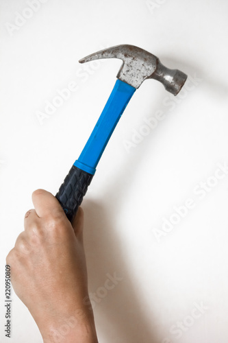 The hammer in the hand on the light backdrop photo