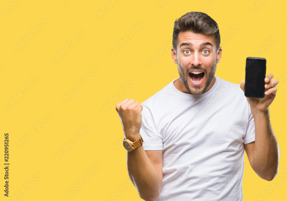Young handsome man showing smartphone screen over isolated background screaming proud and celebrating victory and success very excited, cheering emotion Young handsome man showing smartphone screen over isolated background screaming proud and celebrating victory and success very excited, cheering emotion