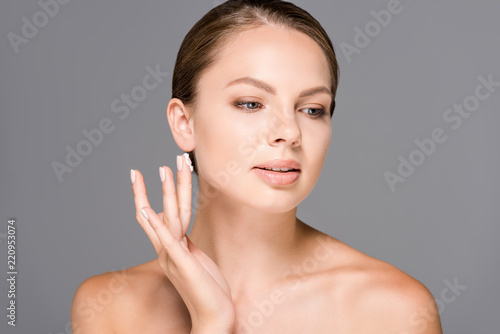 portrait of attractive young woman with face cream looking away isolated on grey