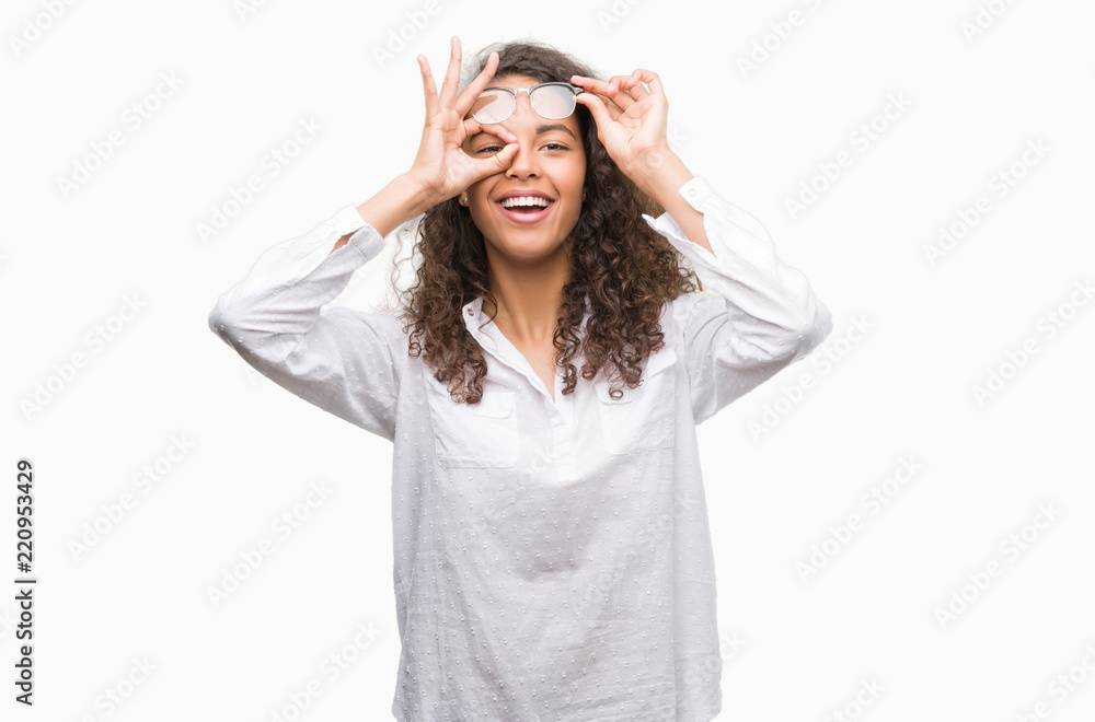 Beautiful young hispanic woman doing ok gesture with hand smiling, eye looking through fingers with happy face. Beautiful young hispanic woman doing ok gesture with hand smiling, eye looking through fingers with happy face.