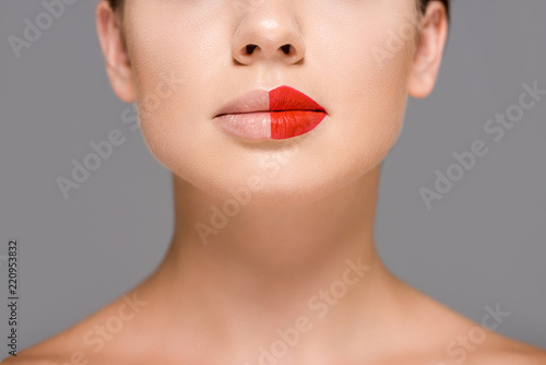 cropped shot of woman with red lipstick on half of mouth isolated on grey