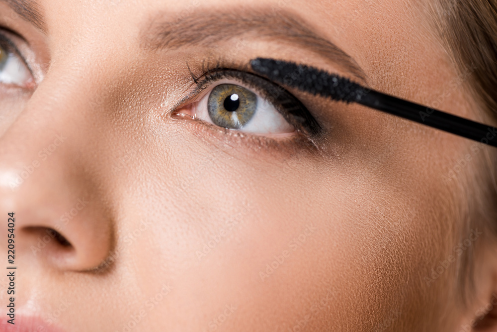 partial view of woman applying black mascara while looking away