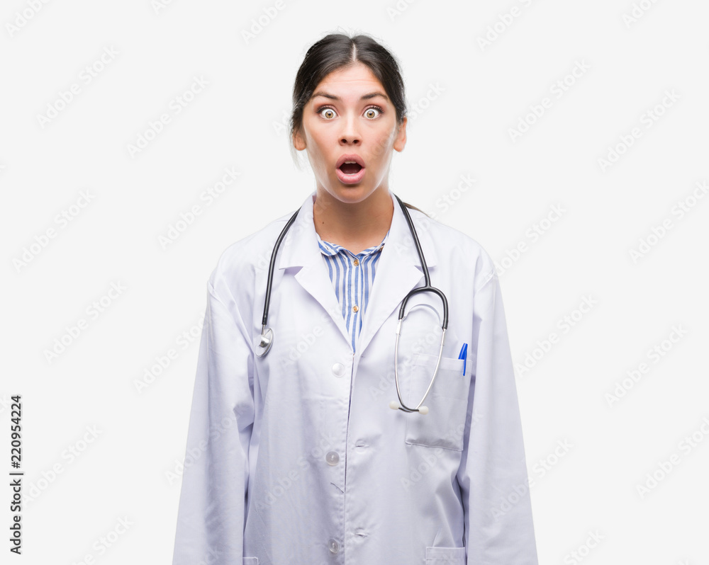 Young hispanic doctor woman scared in shock with a surprise face, afraid and excited with fear expression Young hispanic doctor woman scared in shock with a surprise face, afraid and excited with fear expression