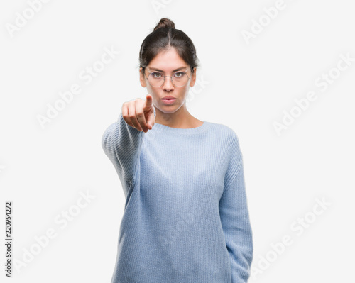 Young beautiful hispanic woman wearing a bun pointing with finger to the camera and to you, hand sign, positive and confident gesture from the front