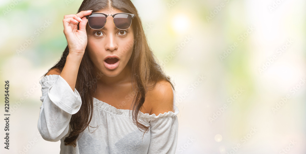 Obraz premium Young beautiful arab woman wearing sunglasses over isolated background afraid and shocked with surprise expression, fear and excited face.