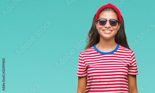 Young beautiful arab woman wearing sunglasses over isolated background with a happy and cool smile on face. Lucky person.
