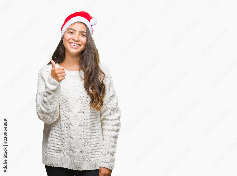Young arab woman wearing christmas hat over isolated background doing happy thumbs up gesture with hand. Approving expression looking at the camera with showing success. Young arab woman wearing christmas hat over isolated background doing happy thumbs up gesture with hand. Approving expression looking at the camera with showing success.
