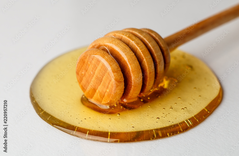 Wooden honey dripper and pouring spot of honey on white background, macro photo Wooden honey dripper and pouring spot of honey on white background, macro photo