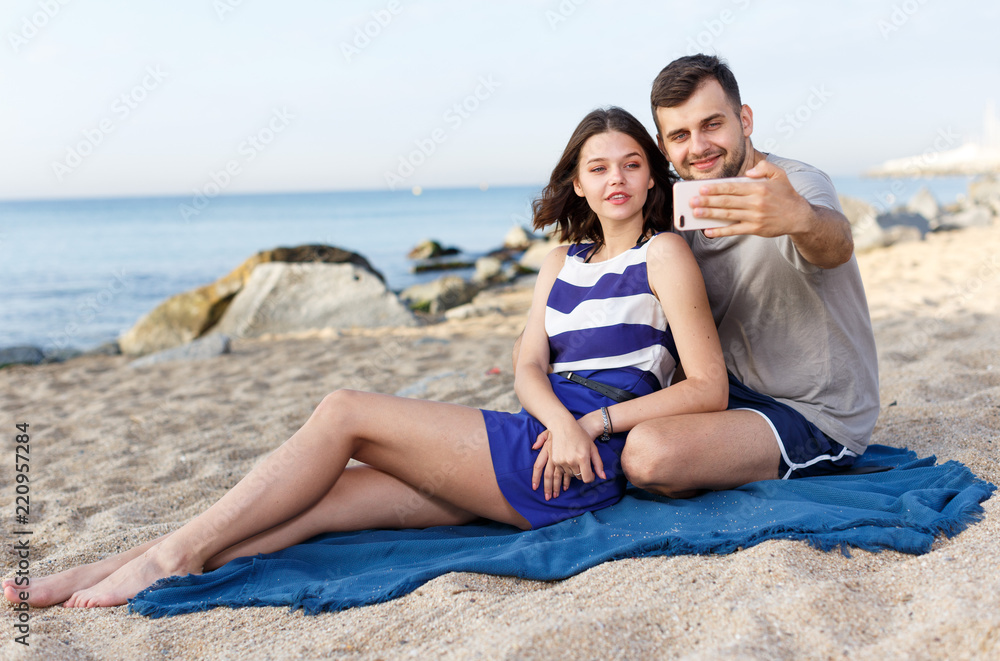 Fototapeta premium Young loving couple resting and taking selfie