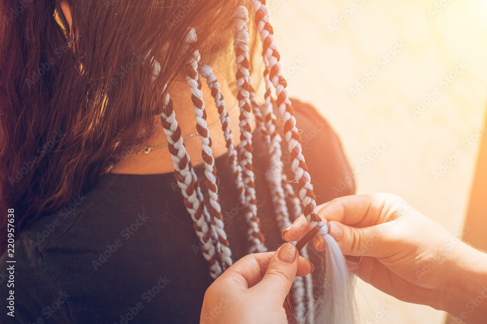 Hairdresser weaves braids with kanekalon to young girl head