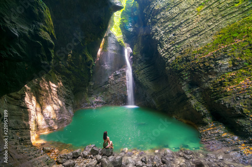 Fashionable girl in swimsuit relaxes in front of the Kozjak Waterfall, Slovenia