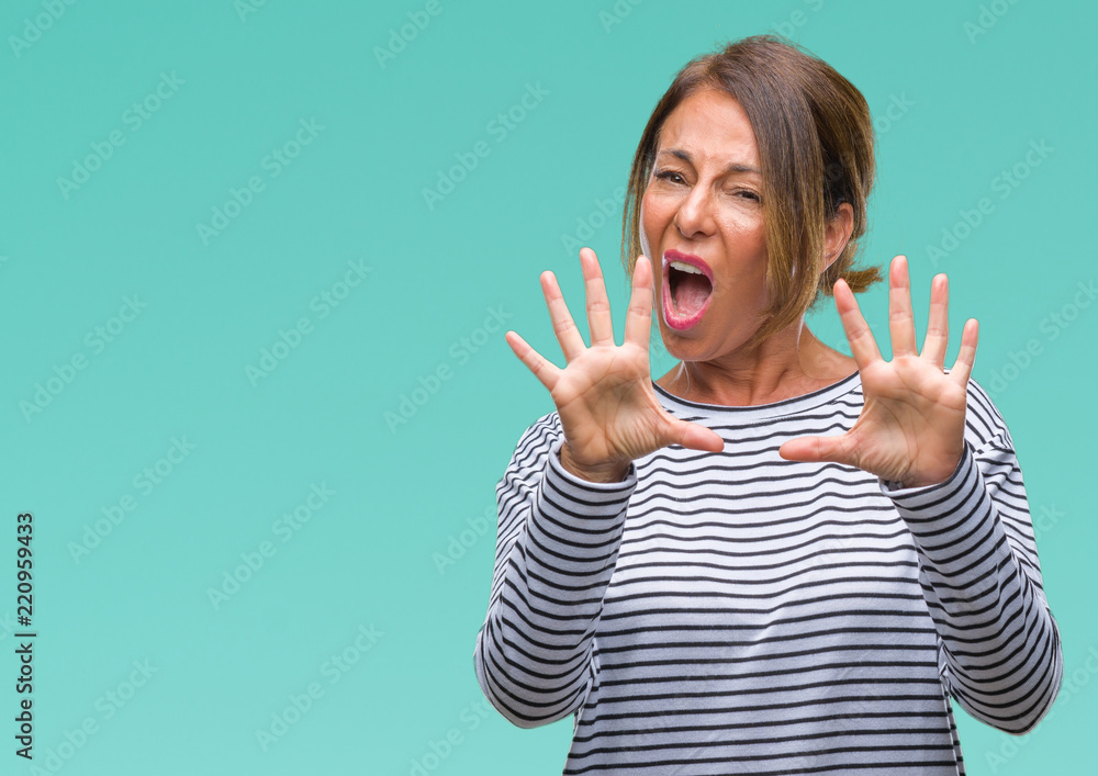 Middle age senior hispanic woman over isolated background afraid and terrified with fear expression stop gesture with hands, shouting in shock. Panic concept. Middle age senior hispanic woman over isolated background afraid and terrified with fear expression stop gesture with hands, shouting in shock. Panic concept.
