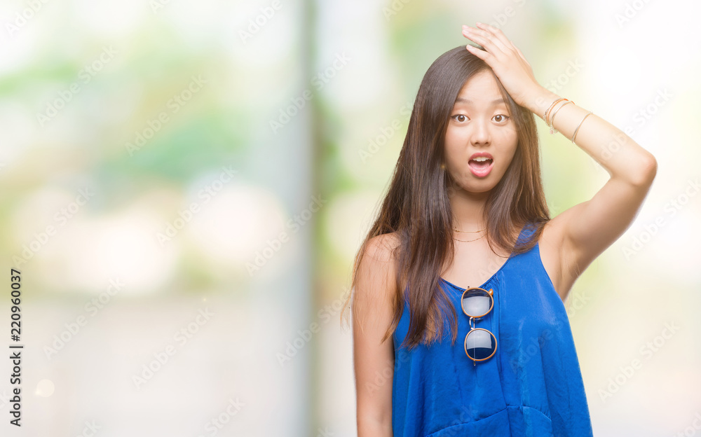 Young asian woman over isolated background surprised with hand on head for mistake, remember error. Forgot, bad memory concept.