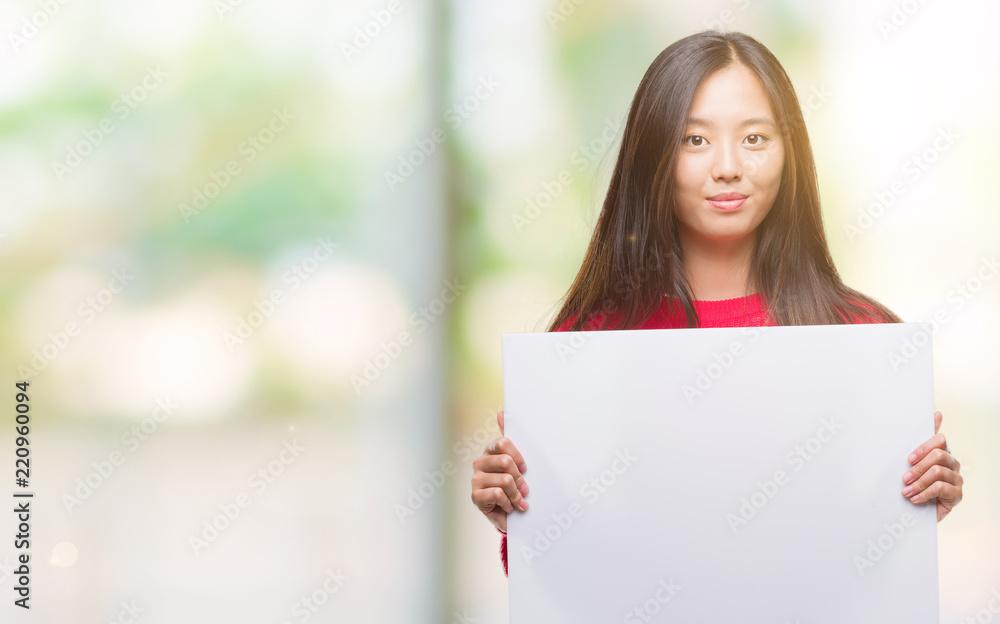 Young asian woman holding banner over isolated background with a confident expression on smart face thinking serious Young asian woman holding banner over isolated background with a confident expression on smart face thinking serious