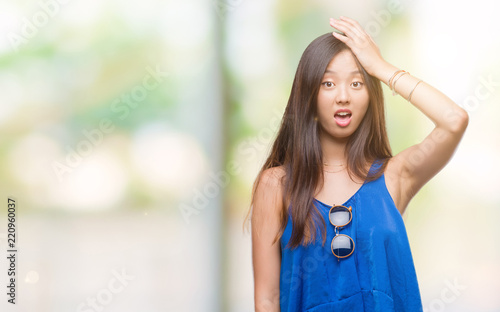Young asian woman over isolated background surprised with hand on head for mistake, remember error. Forgot, bad memory concept.