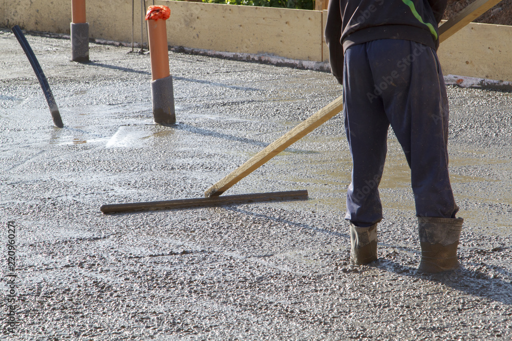 worker leveling fresh concrete slab with a special wooden working tool worker leveling fresh concrete slab with a special wooden working tool