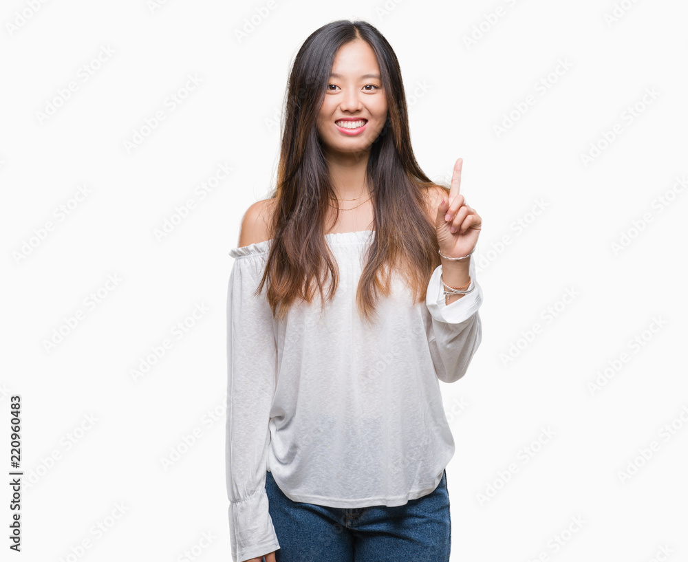 Young asian woman over isolated background showing and pointing up with finger number one while smiling confident and happy. Young asian woman over isolated background showing and pointing up with finger number one while smiling confident and happy.