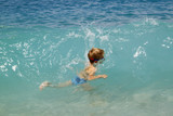 little boy play with splahes waves of the sea