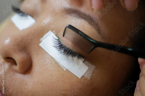 Asian woman got Eyelash Extension Service from professional Lash Stylist to enhance the length, curliness, fullness, and thickness of natural eyelashes. The lashes are applied one at a time using glue photo