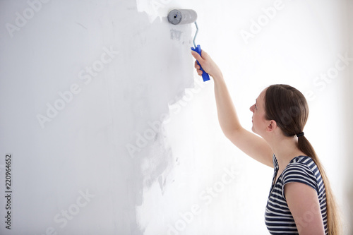 young woman painting wall of her home © mimagephotos