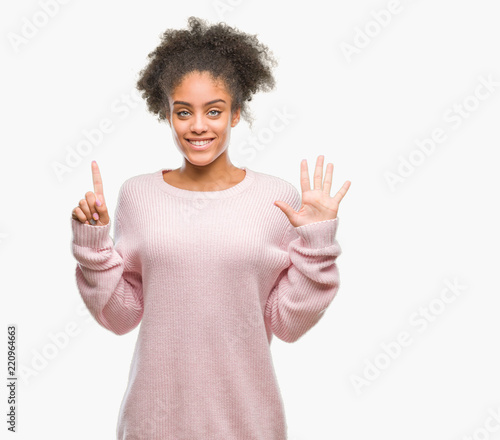 Young afro american woman wearing winter sweater over isolated background showing and pointing up with fingers number six while smiling confident and happy.