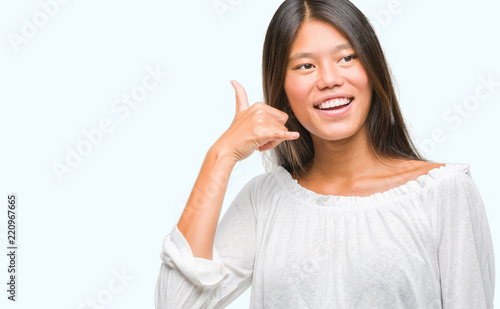 Wallpaper Mural Young asian woman over isolated background smiling doing phone gesture with hand and fingers like talking on the telephone. Communicating concepts. Torontodigital.ca