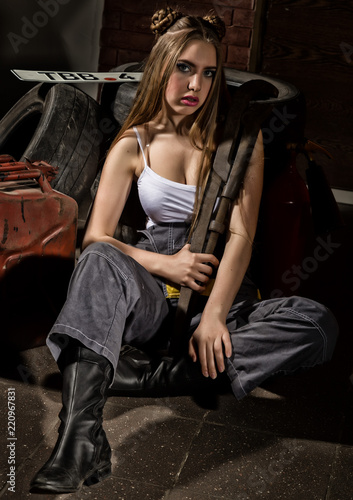 Young impulsive sexy woman dressed as an auto mechanic and welding glasses holding a big wrench