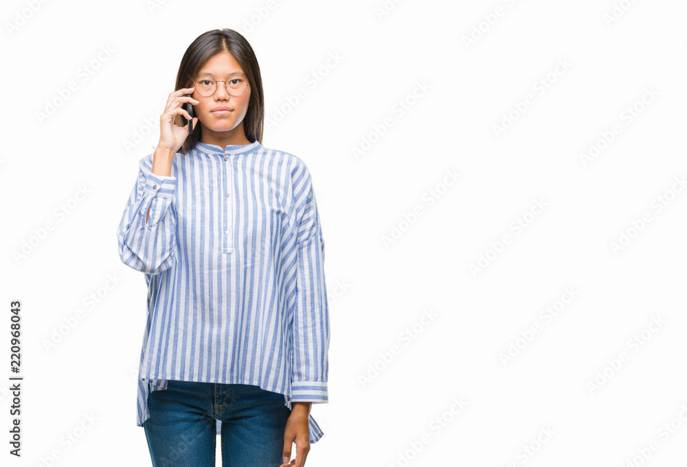 Young asian woman speaking on the phone over isolated background with a confident expression on smart face thinking serious Young asian woman speaking on the phone over isolated background with a confident expression on smart face thinking serious
