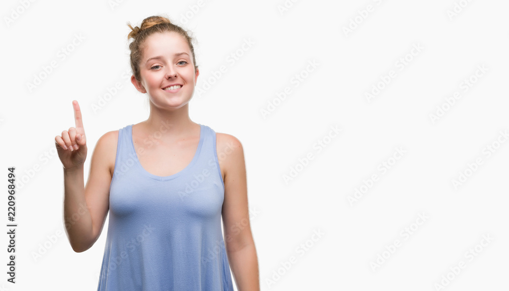 Young blonde woman showing and pointing up with finger number one while smiling confident and happy. Young blonde woman showing and pointing up with finger number one while smiling confident and happy.