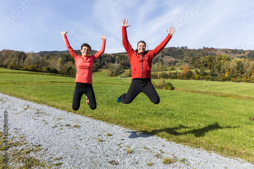 A couple jumping after completing their outdoor exercise in the countride of Bavarian National Forest Park, Germany