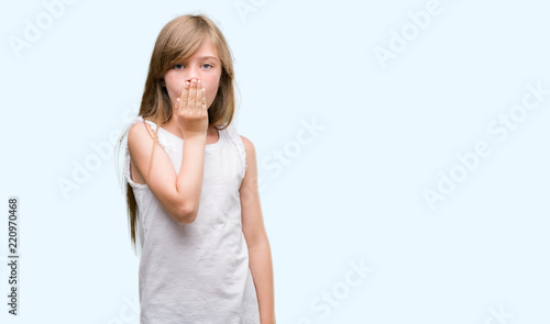 Young blonde toddler cover mouth with hand shocked with shame for mistake, expression of fear, scared in silence, secret concept