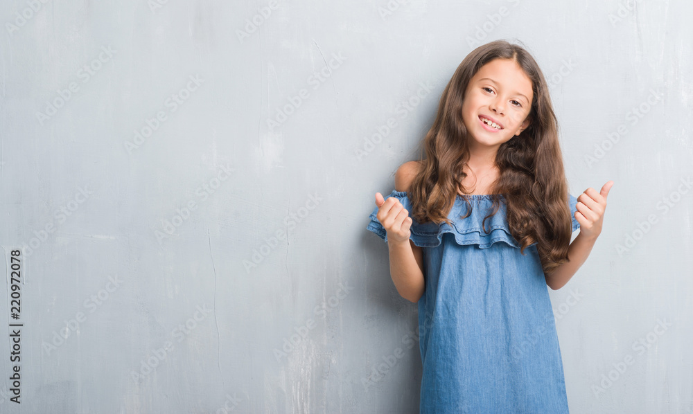 Young hispanic kid over grunge grey wall success sign doing positive gesture with hand, thumbs up smiling and happy. Looking at the camera with cheerful expression, winner gesture. Young hispanic kid over grunge grey wall success sign doing positive gesture with hand, thumbs up smiling and happy. Looking at the camera with cheerful expression, winner gesture.