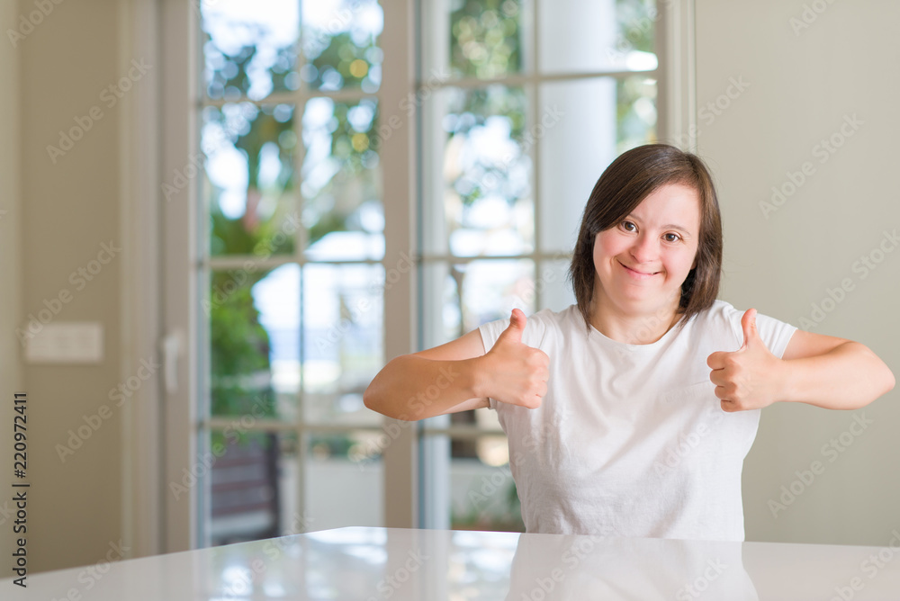 Down syndrome woman at home success sign doing positive gesture with hand, thumbs up smiling and happy. Looking at the camera with cheerful expression, winner gesture. Down syndrome woman at home success sign doing positive gesture with hand, thumbs up smiling and happy. Looking at the camera with cheerful expression, winner gesture.