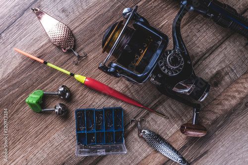 Fishing gear and fishing rod on a wooden background. Fishing supplies, top view