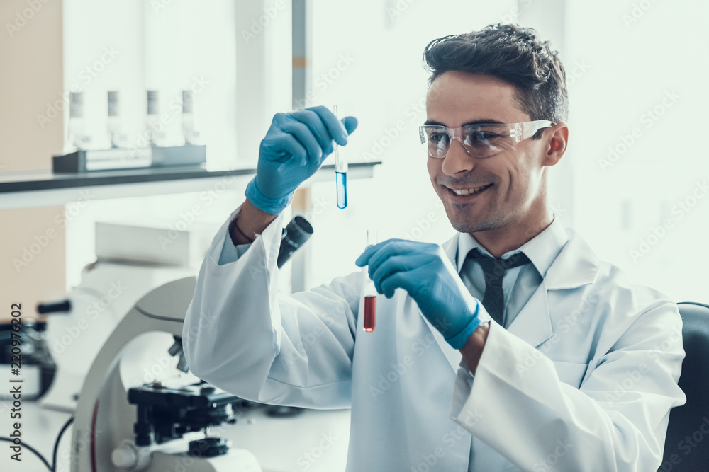 Scientist looks at Liquid Samples in Flasks in Lab Scientist looks at Liquid Samples in Flasks in Lab